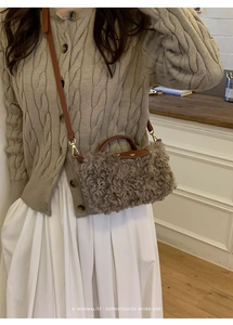 Close-up of grey faux shearling small square bag with leather handles on a model