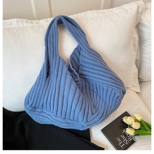 Macro shot of sky blue knitted hobo tote showing thick ribbed texture and handle detail