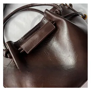 Detailed view of dark brown wax leather bucket bag with drawstring and embossed logo