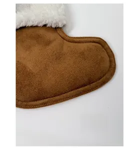 Detailed view of brown suede crossbody bag with soft white faux shearling trim and logo patch