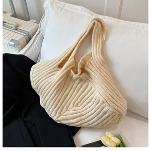 Macro detail of cream knitted tote bag featuring vertical ribbed texture and soft fabric