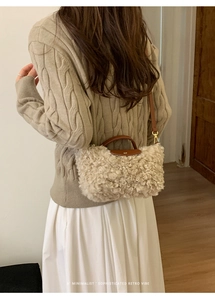 Detail of soft shearling texture and dark brown leather handle on a stylish crossbody bag