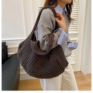 Close-up of deep brown knitted tote bag featuring thick vertical striped texture and wide strap
