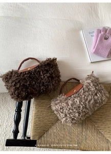 Detail of plush lambskin texture handbags with leather handles and gold metal buttons