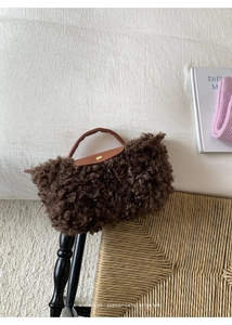 Detail of faux shearling crossbody bag featuring leather trim and gold snap closure