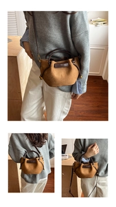 Detail of brown suede bucket bag with leather handles and golden drawstring hardware