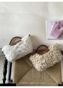 Detail showing plush faux shearling texture and brown leather trim on a crossbody dumpling bag