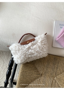 Detail view of the plush white sherpa texture and brown leather strap on a chic handbag