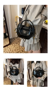 Close-up of black bucket bag with glossy patent leather finish and golden drawstring detail