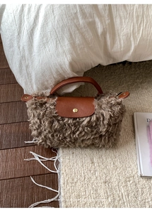 Detail of plush faux shearling handbag with brown leather flap and gold metal snap
