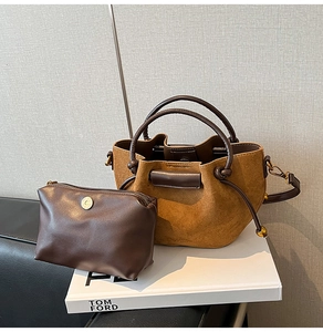 Detail of tan suede bucket bag with matching inner pouch and gold metal hardware