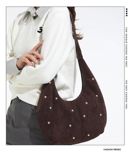 Close-up of dark coffee suede hobo bag with gold rivet studs and leather strap detail