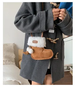 Detail of faux suede boot-shaped crossbody bag with white fur trim and plush pom-poms