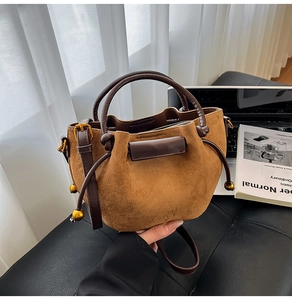 Detail of brown suede drawstring bucket bag with gold hardware and leather strap