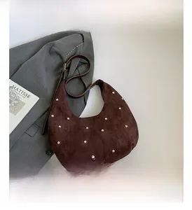 Brown suede hobo bag with gold rivet studs styled with a grey blazer and book