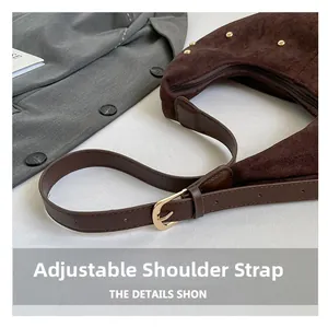 Detail of adjustable leather strap and golden rivets on dark brown suede tote bag