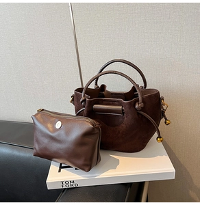Detail of dark brown bucket bag set featuring suede texture and gold metal sphere charm