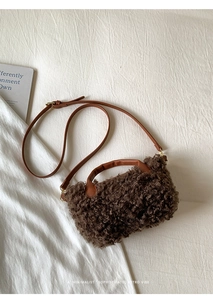 Nahaufnahme braune Lammwoll-Tasche mit Lederriemen auf weichem weißem Stoff
