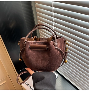 Detail of dark brown suede mini bucket bag with gold ball accent and hardware