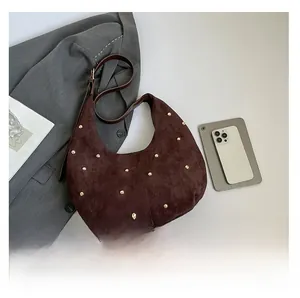 Detail view of coffee suede shoulder bag featuring gold studs and retro half-moon shape