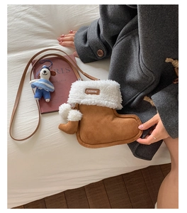 Detail of a brown suede Christmas boot bag with white faux fur trim and pom-pom accents