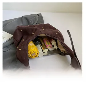 Detail of the brown suede crescent bag showing interior capacity and golden stud rivets