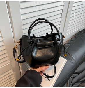 Detailed shot of a black glossy leather bucket bag with gold hardware and drawstring