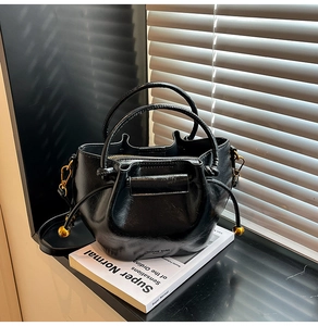 Close-up of black crossbody bag with gold hardware and NINAHE GARO logo on the side