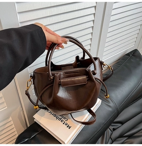 Detail of dark brown glossy PU leather dumpling bag with drawstring and metal beads