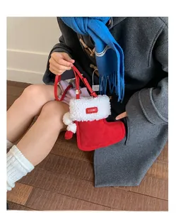 Detail of red suede Christmas sock bag with white faux fur trim and pom-pom accents
