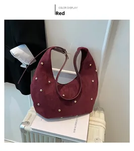 Detail of burgundy suede crescent bag with gold star rivets on a white suitcase