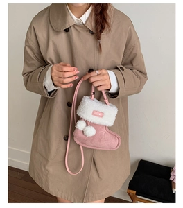 Gros plan sur un sac bottine rose avec col en fausse fourrure et pompons en peluche