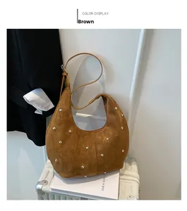 Detailed close-up of brown suede hobo bag with golden rivets and adjustable strap