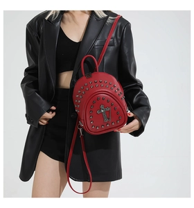 Détail du mini sac à dos en cuir PU rouge avec clous argentés et ornement de croix en métal