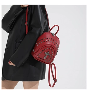 Détail d'un mini sac à dos punk rouge avec clous métalliques et croix sur un mannequin