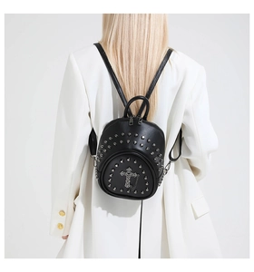 Détail d'un mini sac à dos en cuir noir avec rivets et croix gothique décorative