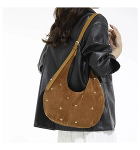 Brown suede hobo bag with gold studs and adjustable strap shown on model's shoulder