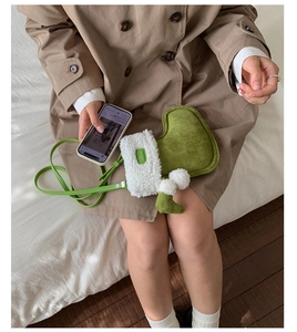 Detail of green plush boot-shaped crossbody bag with white faux fur trim and leather strap