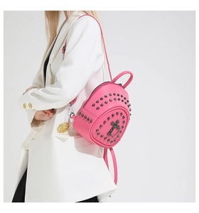 Pink mini backpack with black studs and metal cross detail shown on a model