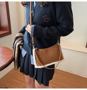 Detailed view of brown leather bag featuring soft white faux shearling trim and strap