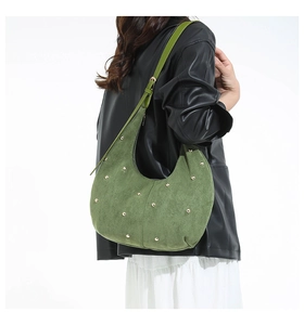 Close-up of green suede hobo bag featuring gold rivet studs and slender shoulder strap