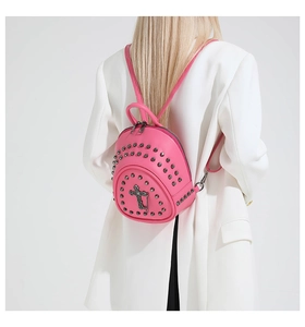 Détail d'un mini sac à dos rose fuchsia avec rivets punk et pendentif croix sur un mannequin