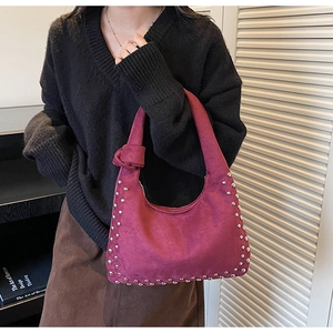 Close-up of wine red suede tote bag with silver rivets and knotted handle detail