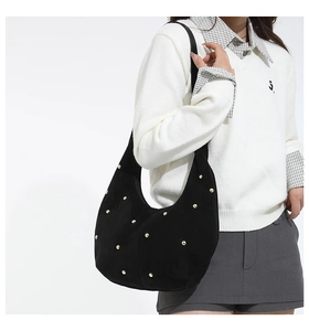 Detail of black suede hobo bag with gold stud embellishments and crescent shape