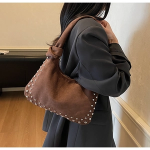 Detail of vintage brown suede shoulder bag featuring silver rivets and knotted strap detail
