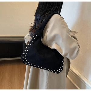 Side view of black faux suede shoulder bag with silver rivet details and bohemian style