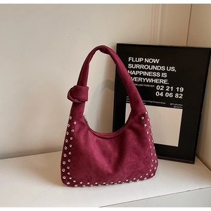 Detailed macro view of burgundy suede hobo bag with silver studs and knotted strap