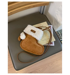 Detail view of a brown plush Christmas stocking-shaped crossbody bag with a white pompom