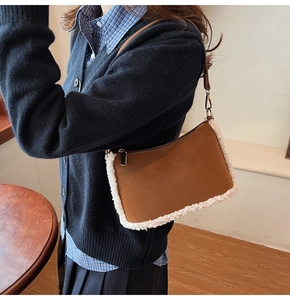 Close-up of brown leather shoulder bag with white fleece trim and metal zipper detail