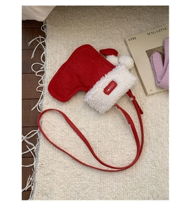 Detail of red Christmas stocking bag with white plush trim and fuzzy pom-poms on cozy rug